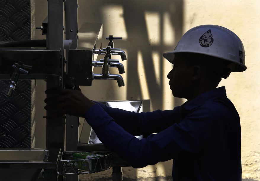 An Indian volunteer of Planet Water foundation, a non-governmental organization based in the U.S. fixes taps of a water filtration tower in a school in Nai Basti Village, some 55 kilometers (35 miles) from in New Delhi, India, Wednesday, March 22, 2017. Schoolchildren cheered and village women clapped as a gush of clean water flowed through a set of gleaming steel taps connected to a newly installed water filtration plant in a dusty north Indian village on Wednesday. (AP Photo/Manish Swarup)