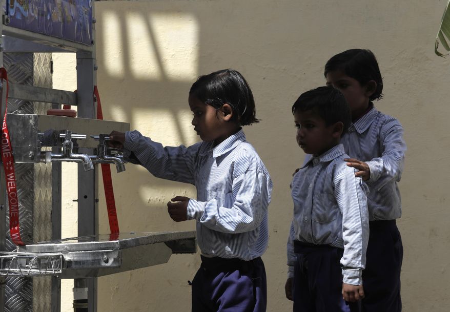 Schoolchildren line up to drink water from a newly set up water filtration tower at their school in Nai Basti Village, some 55 kilometers (35 miles) from in New Delhi, India, Wednesday, March 22, 2017. Schoolchildren cheered and village women clapped as a gush of clean water flowed through a set of gleaming steel taps connected to a newly installed water filtration plant in a dusty north Indian village on Wednesday. (AP Photo/Manish Swarup)