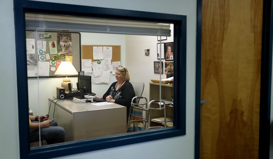 In this Tuesday, March 21, 2017, photo, Mary Lytle-Gaines meets with a client in her office in St. Louis. With her mobile home paid off, the 61-year-old social worker had hoped to semi-retire next year and work part time, but now with insurance premiums likely to rise for her age group and income level she believes that may not be possible. (AP Photo/Jeff Roberson)