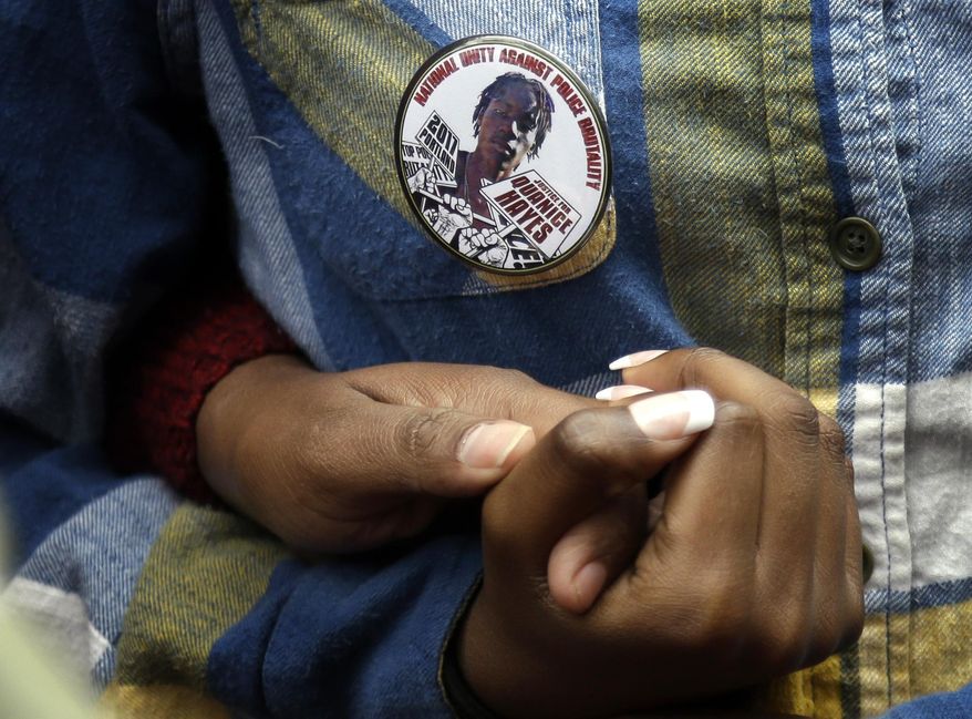 Family members hold hands beneath a button portraying Quanice Hayes during a press conference in Portland, Ore., Wednesday, March 22, 2017. Venus Hayes, the mother the 17-year-old Quanice Hayes, held the news conference after a grand jury declined to indict a Portland police officer on criminal charges in the Feb. 9, 2017, shooting death of her son and is demanding a federal investigation. (AP Photo/Don Ryan)