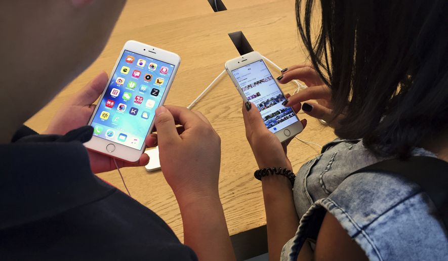 In this Saturday, June 18, 2016, file photo, customers try out Apple iPhone 6s models on display at an Apple Store in Beijing. (AP Photo/Mark Schiefelbein, File)