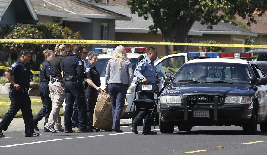 A Sacramento City Police officer, center, carries a bag that was brought from the home where four people were found dead, Thursday, March 23, 2017, in Sacramento, Calif. A suspect is being held in San Francisco. Police are not saying how the four were killed and are not identifying the victims, including their genders and ages. (AP Photo/Rich Pedroncelli)