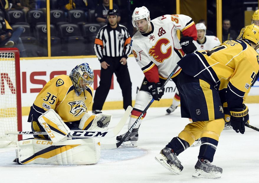 Nashville Predators goalie Pekka Rinne (35), of Finland, stops a shot as Calgary Flames right wing Troy Brouwer (36) looks for the rebound during the first period of an NHL hockey game Thursday, March 23, 2017, in Nashville, Tenn. (AP Photo/Mark Zaleski)