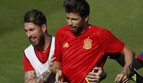 FILE - In this June 24, 2016 file photo, Spain&#39;s Sergio Ramos, left, grabs Gerard Pique during a training session at the Sports Complex Marcel Gaillard in Saint Martin de Re in France. Sergio Ramos and Gerard Pique, defenders from rival clubs Real Madrid and Barcelona are calling a truce and are at peace while with Spain&#39;s national team after exchanging blows through social media and television interviews recently. (AP Photo/Manu Fernandez, File)