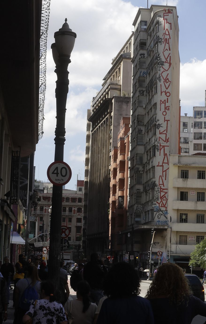 This March 22, 2017 photo shows a building facade covered with a style of street art known as "pichacao" in downtown Sao Paulo, Brazil. Many in Sao Paulo have cheered the mayor's clean up campaign that takes aim at the widely despised style of street art, a generally monochromatic, rune-like calligraphy that covers buildings across the city. (AP Photo/Andre Penner)