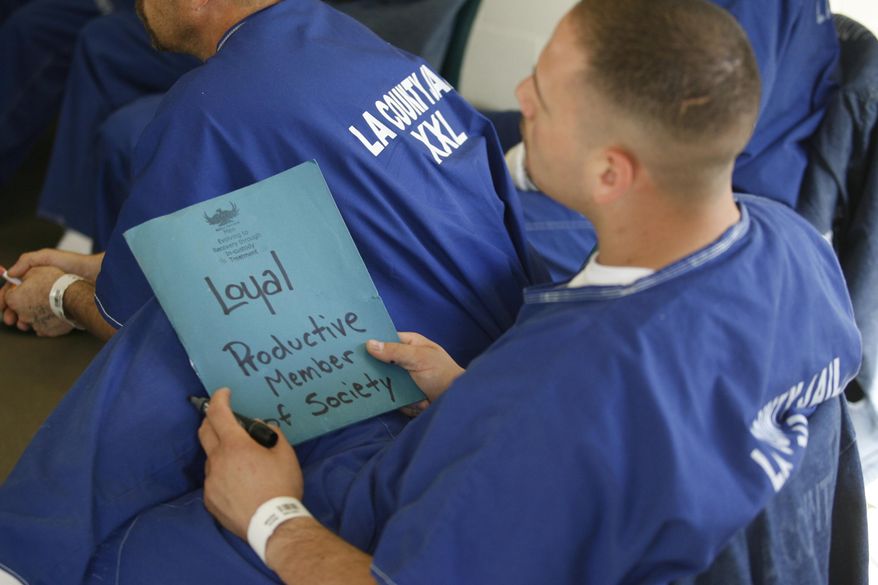 FILE - In this March 10, 2009, file photo, an inmate holds a folder on which he wrote "Loyal Productive Member of Society" during Los Angeles County Sheriff Lt. Gilbert Aguilar's leadership class for inmates at the Pitches Castaic jail in Santa Clarita, Calif. California corrections officials say they are adopting new sentencing rules that aim to trim the state prison population by nearly 9,500 inmates after four years. The regulations released Friday, March 24, 2017, include steps like reducing sentences up to six months for earning a college degree and by up to a month each year for participating in self-help programs like drug counseling. (AP Photo/Damian Dovarganes, File)