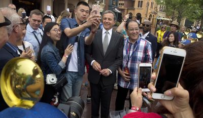 FILE - In this Thursday, June 16, 2016, file photo, Disney CEO Bob Iger poses for selfies with visitors on the opening day of the Disney Resort in Shanghai, China. On Thursday, March 23, 2017, The Walt Disney Co. announced that Iger is getting a one-year contract extension, to July 2, 2019. (AP Photo/Ng Han Guan, File)