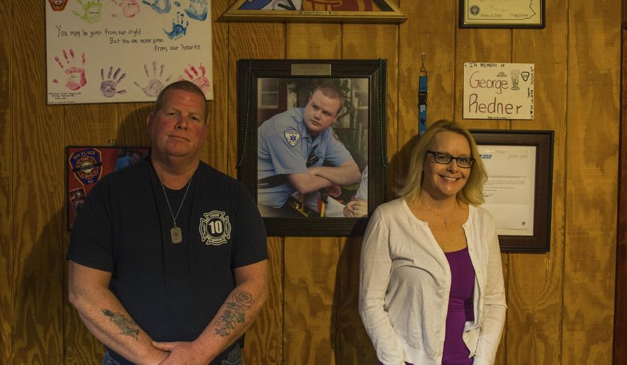 George Redner Jr. and Jacqui Redner pose for a photo in front of a portrait of their son George "Georgie" inside of their home in Levittown, Pa., on March 8, 2017. George committed suicide after suffering from PTSD from working in the Fire/EMS Service. (Nate Smallwood/Pittsburgh Tribune-Review via AP)