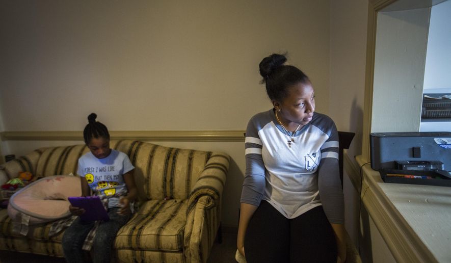 ADVANCE FOR MONDAY, MARCH 27, 2017 -In this Tuesday, Feb. 28, 2017 photo, Trenyce Hadaway, an 8th grader at Landstown Middle School, right, keeps an eye on the street in front of their home in Virginia Beach, Va., for a cab as her sister, Kyliegh Hadaway looks at her tablet before the cab arrives to take her to school. Their family was displaced by Hurricane Matthew and now lives in a different school district but Kyliegh and her older sister Trenyce are attending their original schools until the end of the school year. A cab to take Trenyce to school arrives about an hour later. (Bill Tiernan/The Virginian-Pilot via AP)