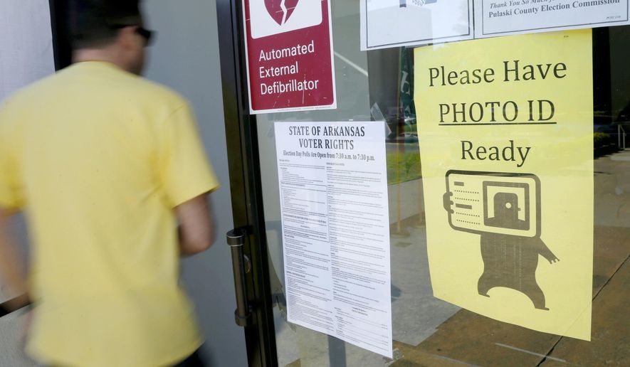 FILE - In this May 5, 2014, file photo, a voter walks past a "Please Have Photo ID Ready" sign as he enters an early-voting polling place in downtown Little Rock, Ark. Arkansas lawmakers approved a measure requiring voters to show photo identification before casting a ballot, and Gov. Asa Hutchinson signed it Friday, March 24, 2017. A similar bill was struck down by a court more than two years ago. (AP Photo/Danny Johnston, File)