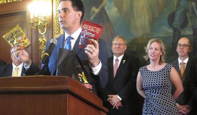 Wisconsin Gov. Scott Walker holds up two bags of Haribo candy when announcing the German-based company would be building its first North American manufacturing plant in southeast Wisconsin not far from Chicago on Thursday, March 23, 2017, in Madison, Wis. (AP Photo/Scott Bauer)