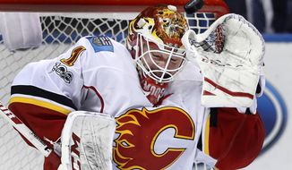 A puck sails over the head of Calgary Flames goalie Brian Elliott during the second period of an NHL hockey game against the St. Louis Blues, Saturday, March 25, 2017, in St. Louis. (AP Photo/Jeff Roberson)