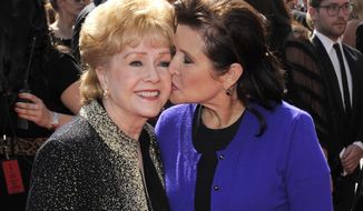 FILE - In this Sept. 10, 2011 file photo, Carrie Fisher kisses her mother, Debbie Reynolds, as they arrive at the Primetime Creative Arts Emmy Awards in Los Angeles. The mother-daughter actresses will be honored at a public memorial on Saturday, March 25, 2017, at the storied Hollywood Hills cemetery where both have been laid to rest. Fisher and Reynolds died one day apart in late December 2016. (AP Photo/Chris Pizzello, File)