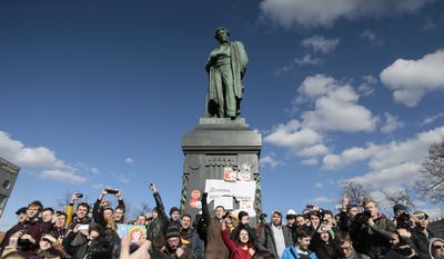 People surround Alexander Pushkin monument with a poster reading: Dimon ( Prime Minister Dmitry Medvedev) Give Money Back, in downtown Moscow, Russia, Sunday, March 26, 2017. Russia's leading opposition figure Alexei Navalny and his supporters aim to hold anti-corruption demonstrations throughout Russia. But authorities are denying permission and police have warned they won't be responsible for "negative consequences" or unsanctioned gatherings. (AP Photo/Ivan Sekretarev)