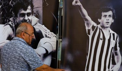 A man walks by the pictures of the French former soccer player and administrator Michel Platini in a museum owned by Philippos Stavrou Platini, who legally adopted his sports hero&#39;s surname, dedicated to Michel Platini, in Mosfiloti, Cyprus on Sunday, March 26, 2017.  A Cypriot fan Michel Platini is renewing a bid to be entered in the Guinness Book of World Records for the biggest collection of Plantini memorabilia. (AP Photo/Petros Karadjias)