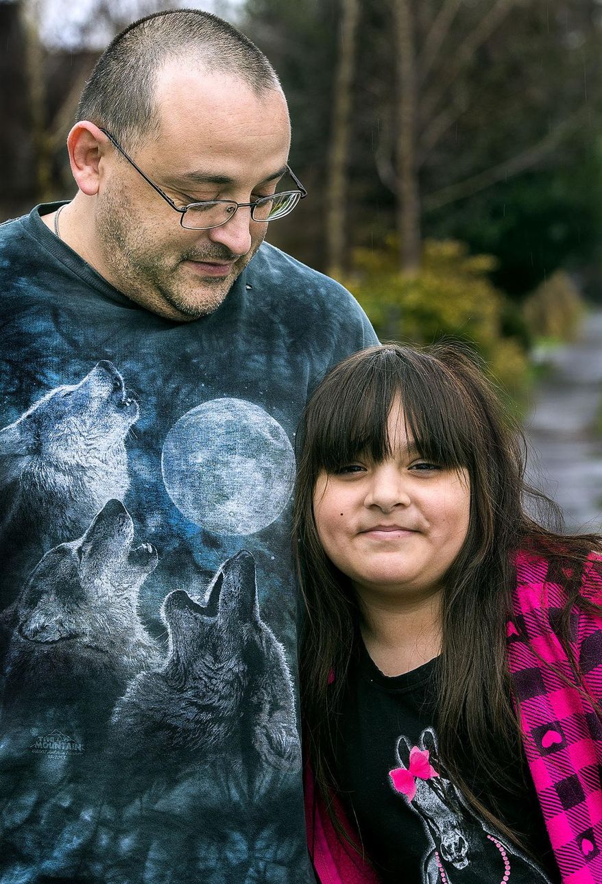 In this March 13, 2017 photo, Mike Romo looks at his daughter, Khia Rom, 8, outside the family’s Highlands home in Longview, Wash. Khia was born with a rare congenital heart condition called double outlet right ventricle and has an additional defect called transposition of the greater arteries. Khia is undergoing her fourth open-heart surgery at the beginning of April. It will be her 18th surgery overall. (Roger Werth/The Daily News via AP)