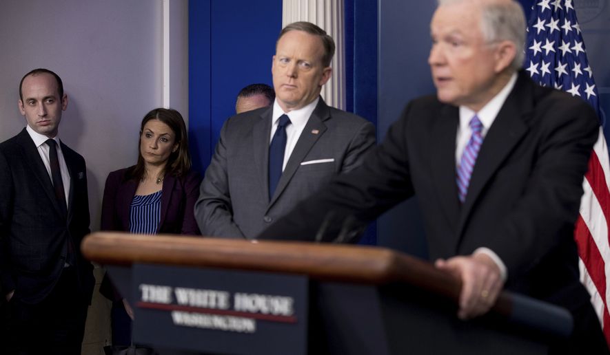 White House Senior Adviser Stephen Miller listens at left as Attorney General Jeff Sessions, right, accompanied by White House press secretary Sean Spicer, talks to the media during the daily press briefing at the White House in Washington, Monday, March 27, 2017. (AP Photo/Andrew Harnik)