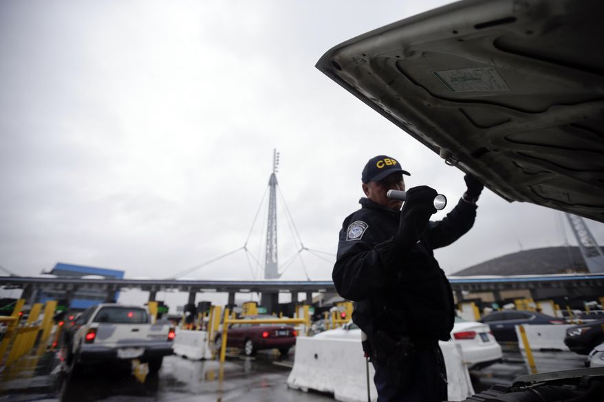 FILE - In this Dec. 3, 2014 file photo, a U.S. Customs and Border Protection (CBP) officer checks under the hood of a car as it waits to enter the U.S. from Tijuana, Mexico through the San Ysidro port of entry in San Diego. A group of First Amendment attorneys is suing the Trump administration over access to data showing how often citizens and visitors had their electronic devices searched and the contents catalogued at the border. (AP Photo/Gregory Bull, File)