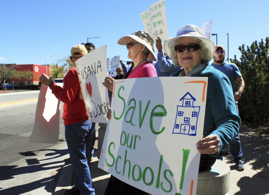 Retired social worker Carol Siemens of Albuquerque, N.M., right, is among protesters who lined a sidewalk outside a luncheon attended by Gov. Susana Martinez in Albuquerque on Monday, March 27, 2017. The two-term Republican governor warned that New Mexico is facing a dire fiscal situation and employee furloughs are possible. (AP Photo/Susan Montoya Bryan)
