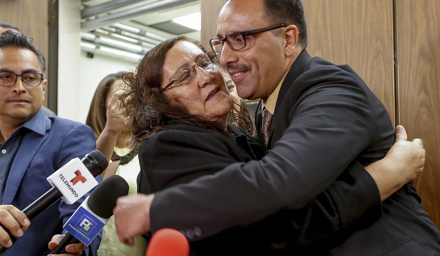Marco Contreras, 41, right, is embraced by his mother, Maria Contreras, as his lawyers cheer following a Los Angeles court hearing during which he was declared factually innocent in Los Angeles on Tuesday, March 28, 2017. Contreras, whose attempted-murder conviction was tossed by a California judge, walked free Tuesday after 20 years in prison. (AP Photo/Damian Dovarganes)