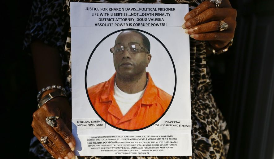 FILE-In this Jan. 18, 2017 file photo, Chrycynthia Davis, mother of Kharon Davis, poses for a portrait inside the doorway of her home while holding a poster she made for her son during an interview for the Associated Press, in Dothan, Ala. Kharon Davis was 22-years-old when he was arrested on a capitol murder charge in 2007 and booked into the Houston County Jail. Alabama prosecutors said Monday, March 27, 2017, they will not seek the death penalty against Davis who has been jailed for nearly 10 years while he awaits trial. (AP Photo/Brynn Anderson, File)