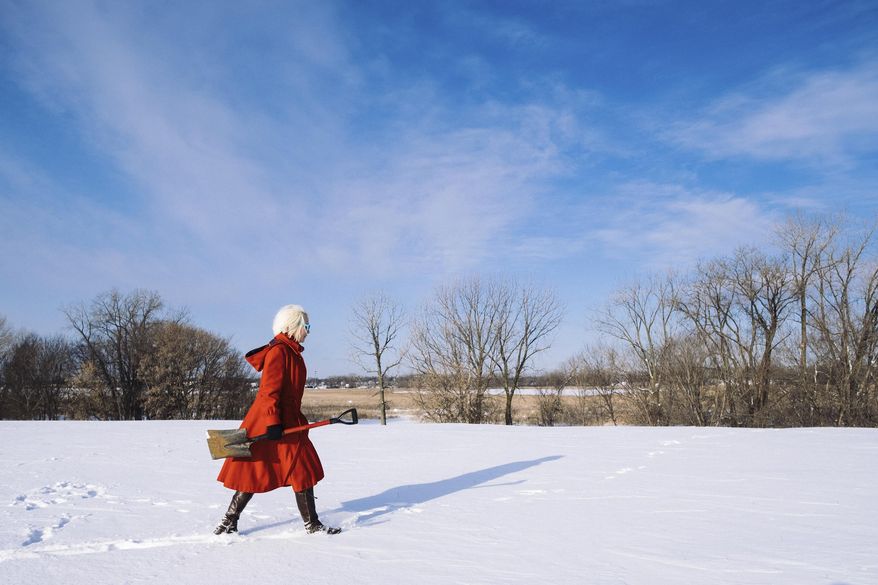 Katie Carrot carries a shovel through the fresh spring snow on her way to one of the stick forts she has constructed in parks around the Twin Cities in Minneapolis on Monday, March 13, 2017. The forts, which Carrot calls environmental sculptures, are made of large branches and stone, one of them even features a "tile floor" made of large flat rocks. (Evan Frost/Minnesota Public Radio via AP)