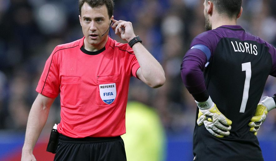 Referee Felix Zwayer, left, from Germany holds his earphone during the international friendly soccer match between France and Spain at the Stade de France in Paris, France, Tuesday, March 28, 2017. (AP Photo/Christophe Ena)