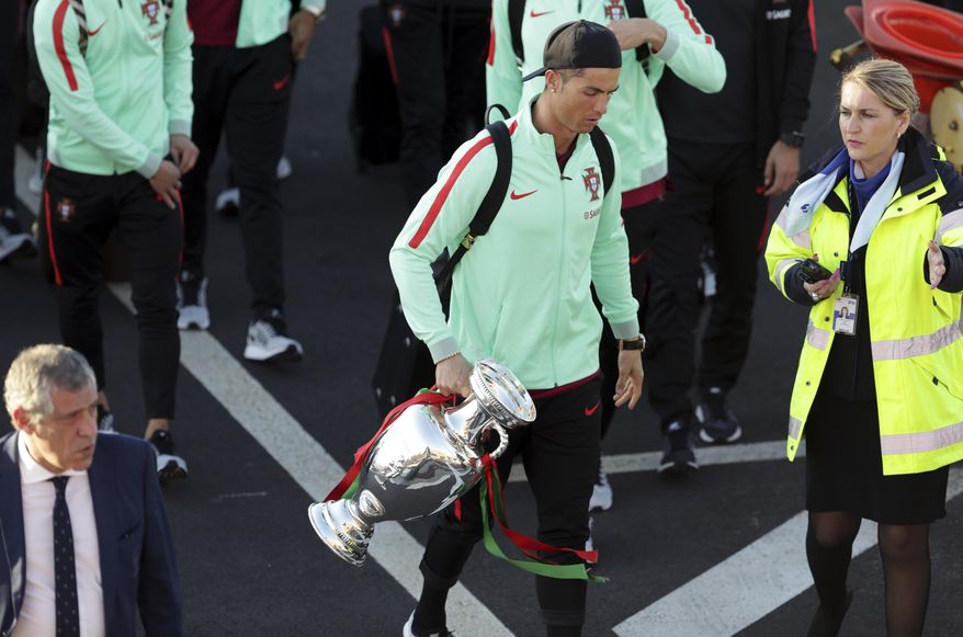 Portugal&#39;s Cristiano Ronaldo carries the Euro 2016 European soccer championship trophy as the Portugal team arrives at the Madeira airport outside Funchal, the capital of Madeira island, Portugal, Monday, March 27 2017. Ronaldo will play in his hometown of Funchal Tuesday when Portugal faces Sweden in a friendly soccer match. (AP Photo/Armando Franca)