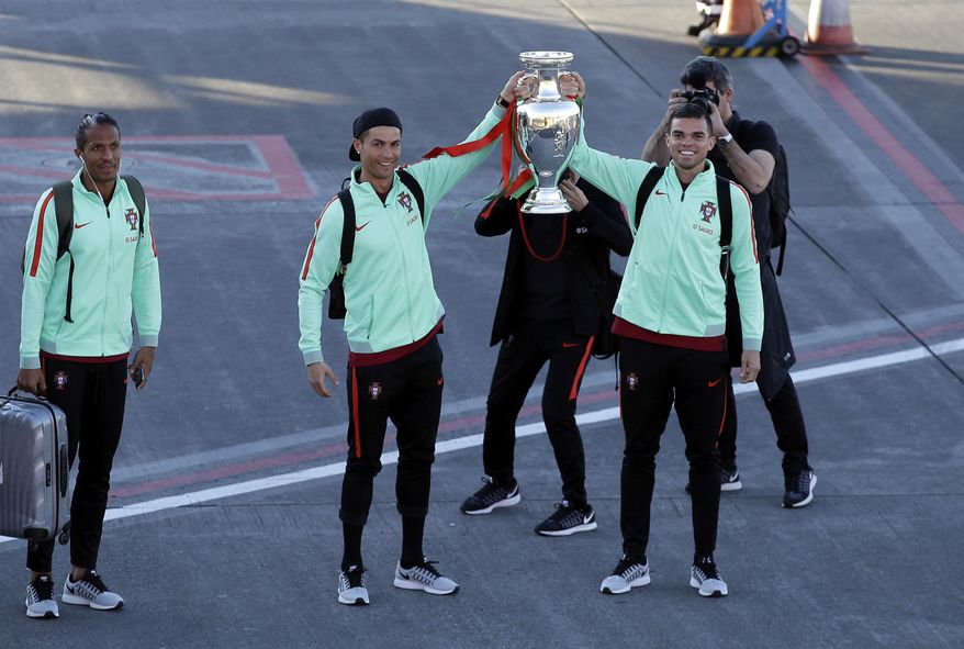 Portugal&#39;s Cristiano Ronaldo and Pepe, right, show off the Euro 2016 European soccer championship trophy as they arrive at the Madeira airport outside Funchal, the capital of Madeira island, Portugal, Monday, March 27 2017.  At left is teammate Bruno Alves. Ronaldo will play in his hometown of Funchal Tuesday when Portugal faces Sweden in a friendly soccer match. (AP Photo/Armando Franca)