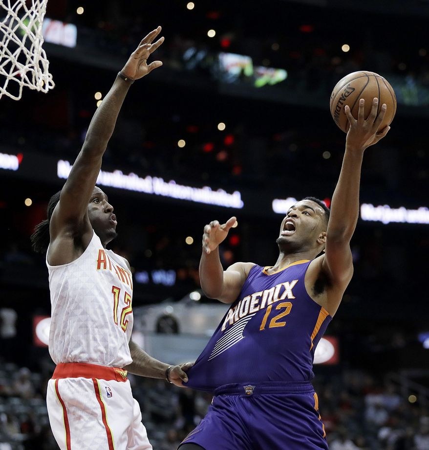 Atlanta Hawks' Taurean Prince, left, defends against the shot of Phoenix Suns' TJ Warren in the first quarter of an NBA basketball game in Atlanta, Tuesday, March 28, 2017. (AP Photo/David Goldman)