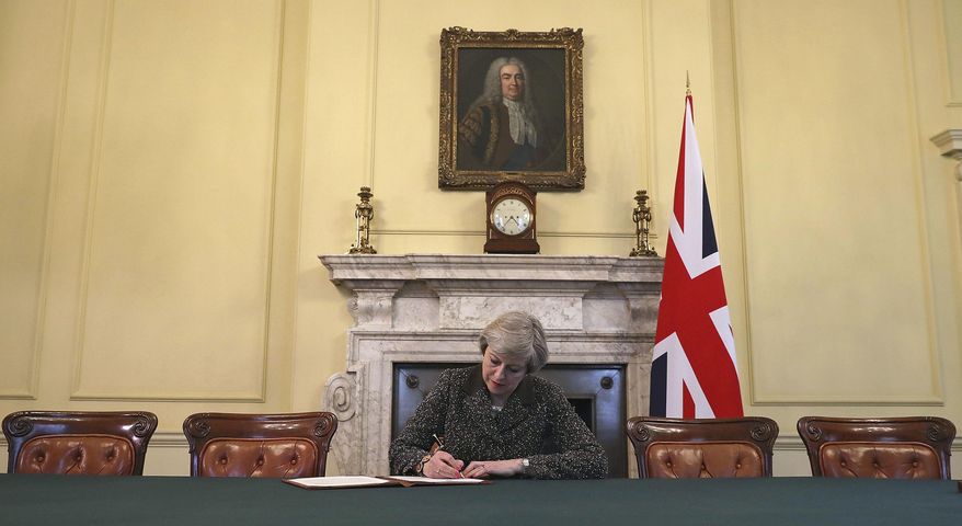 Britain&#39;s Prime Minister Theresa May, sitting below a painting of Britain&#39;s first Prime Minister Robert Walpole, signs the official letter to European Council President Donald Tusk, in 10 Downing Street, London, Tuesday March 28, 2017, invoking Article 50 of the bloc&#39;s key treaty, the formal start of exit negotiations. Britons voted in June to leave the bloc after four decades of membership. (Christopher Furlong/Pool Photo via AP)
