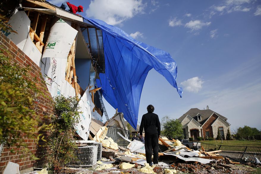 John Hampton stands outside his brother's house that was damaged following a storm early in the morning in Rockwall, Texas on Wednesday, March 29, 2017. A powerful storm system with winds exceeding 60 mph has damaged homes in suburban Dallas, knocked out power to tens of thousands across Texas and brought heavy rain that inundated some areas. (Rose Baca/The Dallas Morning News via AP)
