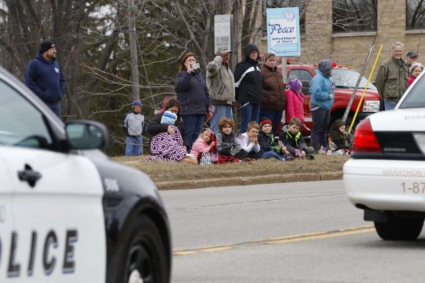 People line on Schofield Avenue Wednesday, March 29, 2017, to pay respect and solute as Everest Metro Police Detective Jason Weiland procession moves through in Schofield, Wis. Weiland was killed in the line of duty during a string of deadly shootings in Rothschild on March 22, 2017, that left three others dead. (T'xer Zhon Kha/The Post-Crescent via AP)
