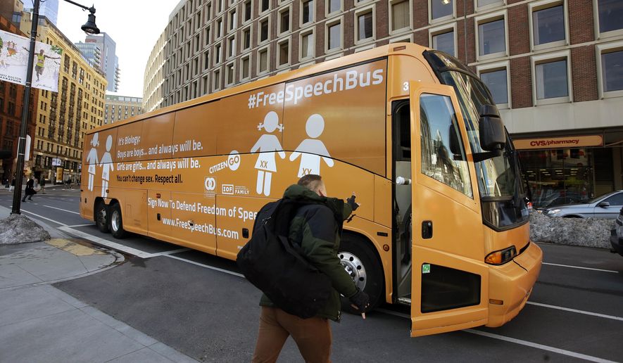 A protestor throws a coffee cup into the "Free Speech Bus" painted with the words "boys are boys" and "girls are girls," parked outside City Hall, Thursday, March 30, 2017, in Boston. A spokesman for the group behind the bus said organizers are pushing back against greater acceptance of transgender people. (AP Photo/Steven Senne)