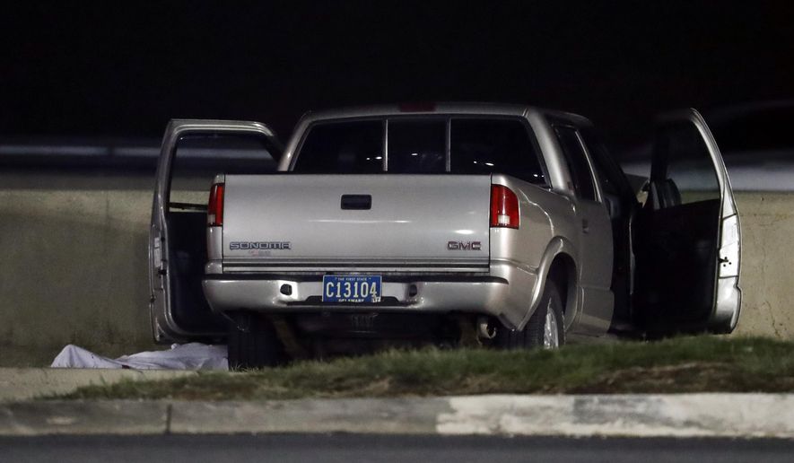 A body is covered by a sheet next to a vehicle at the scene where authorities say a New Jersey state police officer fatally shot a man during an investigation at the Molly Pitcher service area, Thursday, March 30, 2017, in Cranbury, N.J. No police officers were hurt in the shooting on the service area, which serves the New Jersey Turnpike. (AP Photo/Julio Cortez)