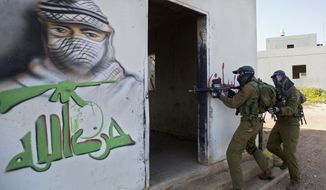 In this Wednesday, March 29, 2017 photo, Israeli soldiers train with paintball guns during a drill at an Army base near Elyakim, Israel. Between myriad concrete buildings with Arabic graffiti that are designed to simulate a typical Lebanese village, dozens of Israeli officers are gearing up for their next battle with Hezbollah guerrillas. The drill at a base in northern Israel takes on added significance in the wake of rising tensions between the old adversaries. Arabic reads, &amp;quot;Hezbollah.&amp;quot; (AP Photo/Sebastian Scheiner)