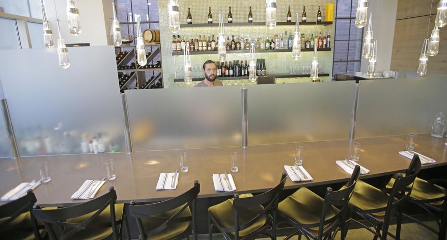 This Wednesday, March 29, 2017, photo, Current Fish & Oyster Restaurant bartender Wren Kennedy looks on from behind the Zion Curtain at the bar, in Salt Lake City. At Current Fish & Oyster Restaurant, a frosted glass wall covering a long, glossy bar will come down at the stroke of midnight on July 1, according to Joel LaSalle, one of the restaurant's owners. "Not only is it ugly and covers up a beautiful bar, but it's costing us thousands of dollars in sales each month," Some Utah restaurants are counting down the days until a new liquor law takes effect this summer, allowing eateries to take stop using walls and partitions that prevent customers from seeing their alcoholic drink being mixed and poured. (AP Photo/Rick Bowmer)
