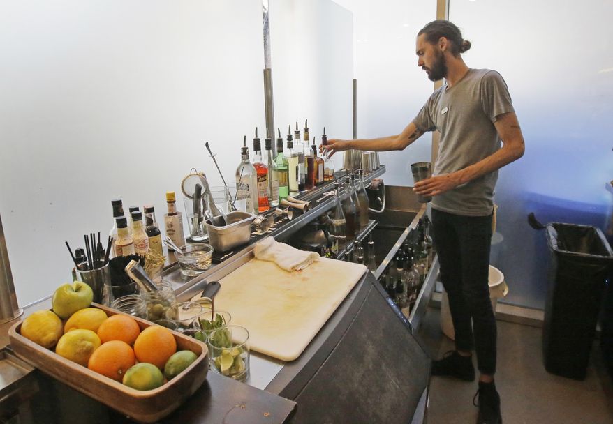 This Wednesday, March 29, 2017, photo, Current Fish & Oyster Restaurant bartender Wren Kennedy prepares a drink behind the Zion Curtain, in Salt Lake City. At Current Fish & Oyster Restaurant, a frosted glass wall covering a long, glossy bar will come down at the stroke of midnight on July 1, according to Joel LaSalle, one of the restaurant's owners. "Not only is it ugly and covers up a beautiful bar, but it's costing us thousands of dollars in sales each month," Some Utah restaurants are counting down the days until a new liquor law takes effect this summer, allowing eateries to take stop using walls and partitions that prevent customers from seeing their alcoholic drink being mixed and poured. (AP Photo/Rick Bowmer)