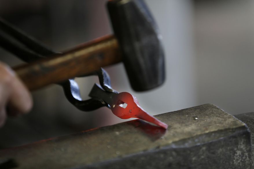 John Lundemo works on a sword guard at an anvil in his workshop in New Hampton, N.Y., Thursday, March 2, 2017. (AP Photo/Seth Wenig)