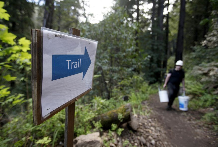 In this photo taken Thursday, March 30, 2017, contractor Tom Massaglia hauls construction equipment up the new Pfeiffer Canyon foot trail that is open to residents traveling around the former Pfeiffer Canyon bridge in Big Sur, Calif. A Big Sur access foot trail has reconnected the two parts of the town that were divided after a bridge collapsed recently. Heavy rains this winter damaged the span on iconic Highway 1 beyond repair, splitting the touristy area in two and stranding more than 400 residents on one side. Visitors have been blocked from reaching part of the community known for its luxury spas, posh hotels and scenic retreats. (Vern Fisher/Monterey Herald via AP)