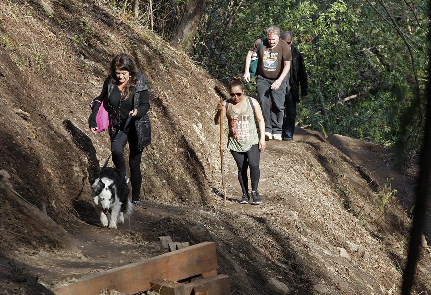In this photo taken Thursday, March 30, 2017, people walk south on the new Pfeiffer Canyon foot trail that is open to residents traveling around the former Pfeiffer Canyon bridge in Big Sur, Calif. A Big Sur access foot trail has reconnected the two parts of the town that were divided after a bridge collapsed recently. Heavy rains this winter damaged the span on iconic Highway 1 beyond repair, splitting the touristy area in two and stranding more than 400 residents on one side. Visitors have been blocked from reaching part of the community known for its luxury spas, posh hotels and scenic retreats. (Vern Fisher/Monterey Herald via AP)
