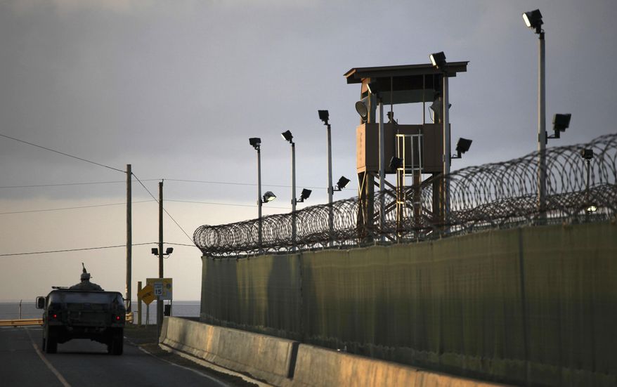 In this March 30, 2010, file photo, reviewed by the U.S. military, a U.S. trooper stands in the turret of a vehicle with a machine gun, left, as a guard looks out from a tower at the detention facility of Guantanamo Bay U.S. Naval Base in Cuba. (AP Photo/Brennan Linsley, File)