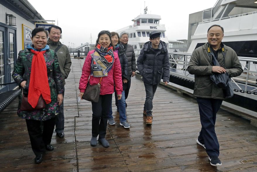 In this March 27, 2017, photo, tourists from China walk to board a boat for a harbor tour in Boston. In cities across the country, the American hospitality industry is stepping up efforts to make Chinese visitors feel more welcome. (AP Photo/Elise Amendola)