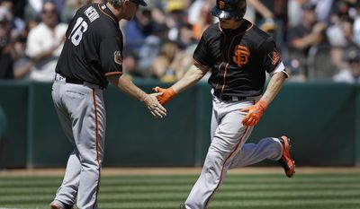 San Francisco Giants&#x27; Nick Hundley, right, is congratulated by third base coach Phil Nevin (16) after hitting a grand slam off Oakland Athletics&#x27; Andrew Triggs in the fourth inning of an exhibition baseball game Saturday, April 1, 2017, in Oakland, Calif. (AP Photo/Ben Margot)