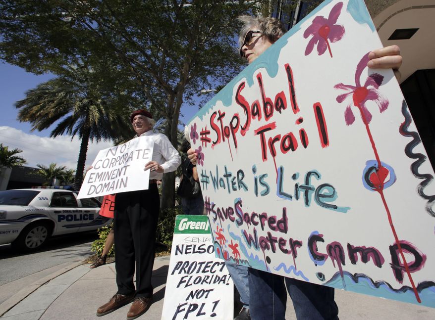 FILE - In this Feb. 14, 2017 file photo, Sabal Trail pipeline protesters hold signs against the pipeline project in front of the office of U.S. Sen. Bill Nelson in Coral Gables, Fla. The Sabal Trail is an underground natural gas pipeline project from Alabama to Florida. Prolonged protests in North Dakota failed to stop the flow of oil through the Dakota Access pipeline. But they've provided inspiration for protests against pipelines around the country. Tactics used in North Dakota such as resistance camps, social media and online fundraising are now being used against pipeline projects in nearly a dozen states. (AP Photo/Alan Diaz, File)