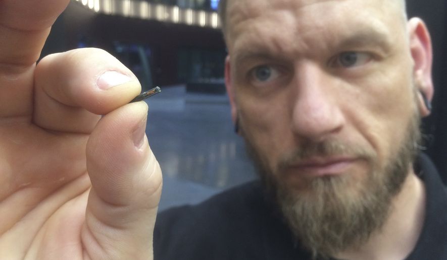 Self-described body hacker Jowan Osterlund from Biohax Sweden holds a small microchip implant, similar to those implanted into workers at the Epicenter digital innovation business center, during a party at the co-working space in central Stockholm, Tuesday, March 14, 2017. Microchips are being implanted into volunteers to help them open doors and operate office equipment, and its become so popular that members of the Epicenter cyborg club hold regular parties for those with the tiny chips embedded in their hands. (AP Photo/James Brooks)