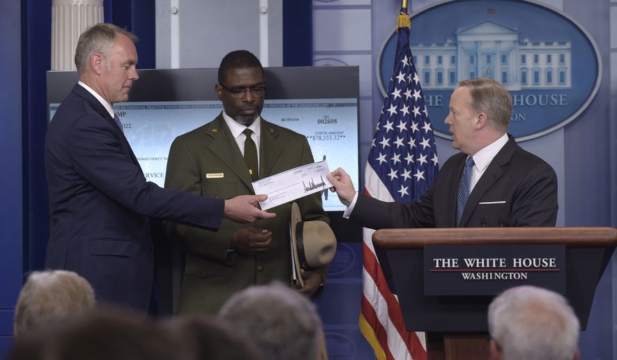 White House press secretary Sean Spicer, right, holds up a check during the daily briefing with Interior Secretary Ryan Zinke, left, and Harpers Ferry National Historic Park Superintendent Tyrone Brandyburg, center, at the White House in Washington, Monday, April 3, 2017. President Donald Trump gave his first quarter salary to the National Park Service. (AP Photo/Susan Walsh)
