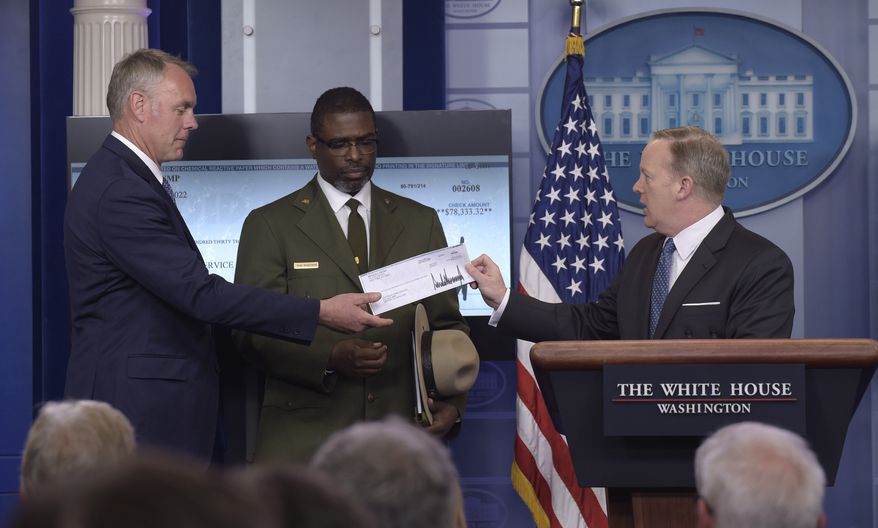 White House press secretary Sean Spicer, right, holds up a check during the daily briefing with Interior Secretary Ryan Zinke, left, and Harpers Ferry National Historic Park Superintendent Tyrone Brandyburg, center, at the White House in Washington, Monday, April 3, 2017. President Donald Trump gave his first quarter salary to the National Park Service. (AP Photo/Susan Walsh)