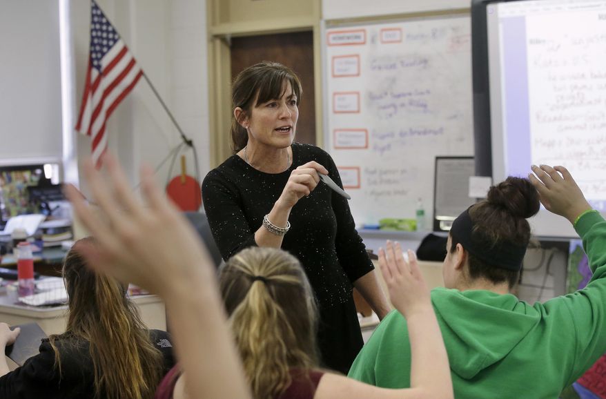 In this Wednesday, March 8, 2017 photo high school teacher Natalie O'Brien, center, calls on students during a civics class called "We the People," at North Smithfield High School in North Smithfield, R.I. More states are requiring graduating high school students to know at least as much about the U.S. founding documents as immigrants passing a citizenship test. (AP Photo/Steven Senne)
