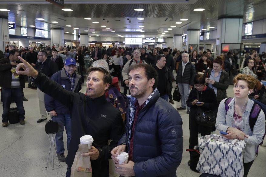 Passengers look up to a train schedule board while waiting in New York's Penn Station, Monday, April 3, 2017. New Jersey Transit said one of its trains derailed while pulling into the station at a slow speed. There were no immediate reports of serious injuries, but New Jersey Transit and Amtrak had service delays. The derailment comes a week and a half after an Amtrak train partially derailed as it pulled out of Penn Station. (AP Photo/Mark Lennihan)